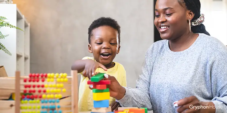 Small boy and a teacher counting stacked colorful blocks