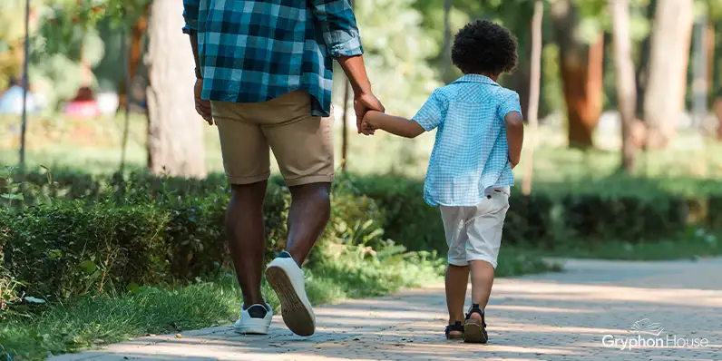 Adult and child walking along a sidewalk