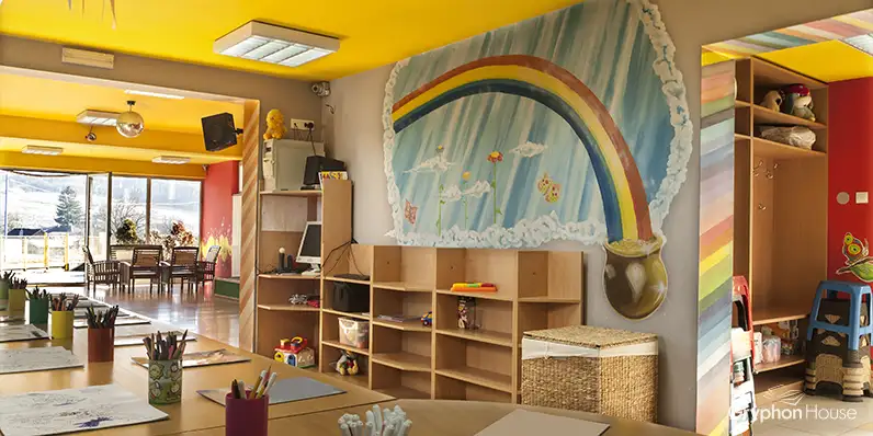 Furnished preschool classroom with a large rainbow mural on one wall