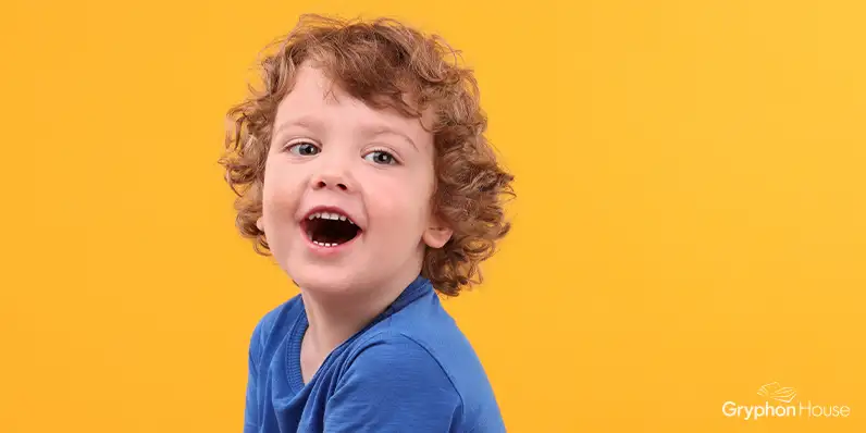 Young boy smiling open mouthed agains a bright yellow background